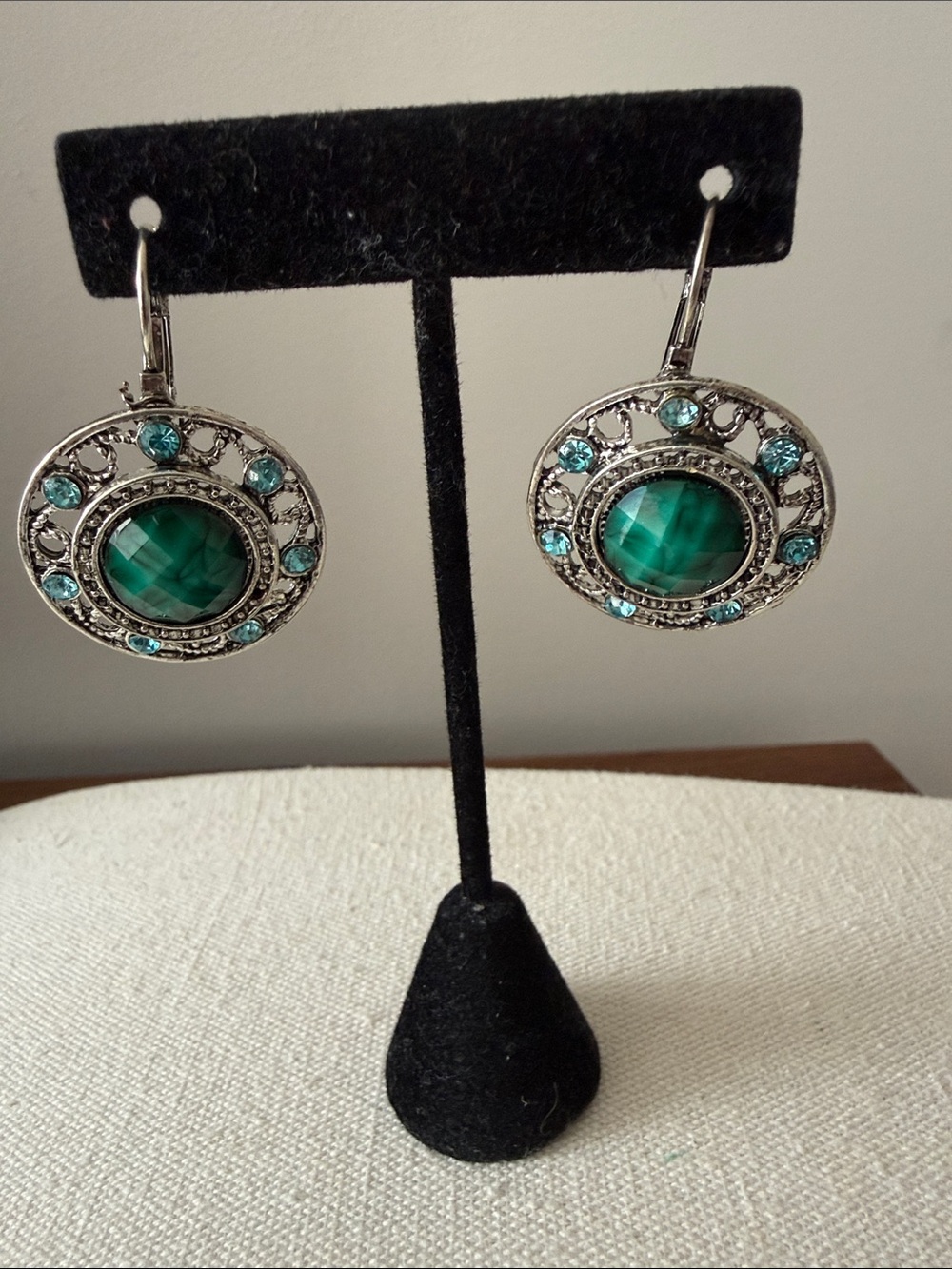 Round Lever Back Drop Earrings with Green Stone Haloed by Silver Tone Filagree.